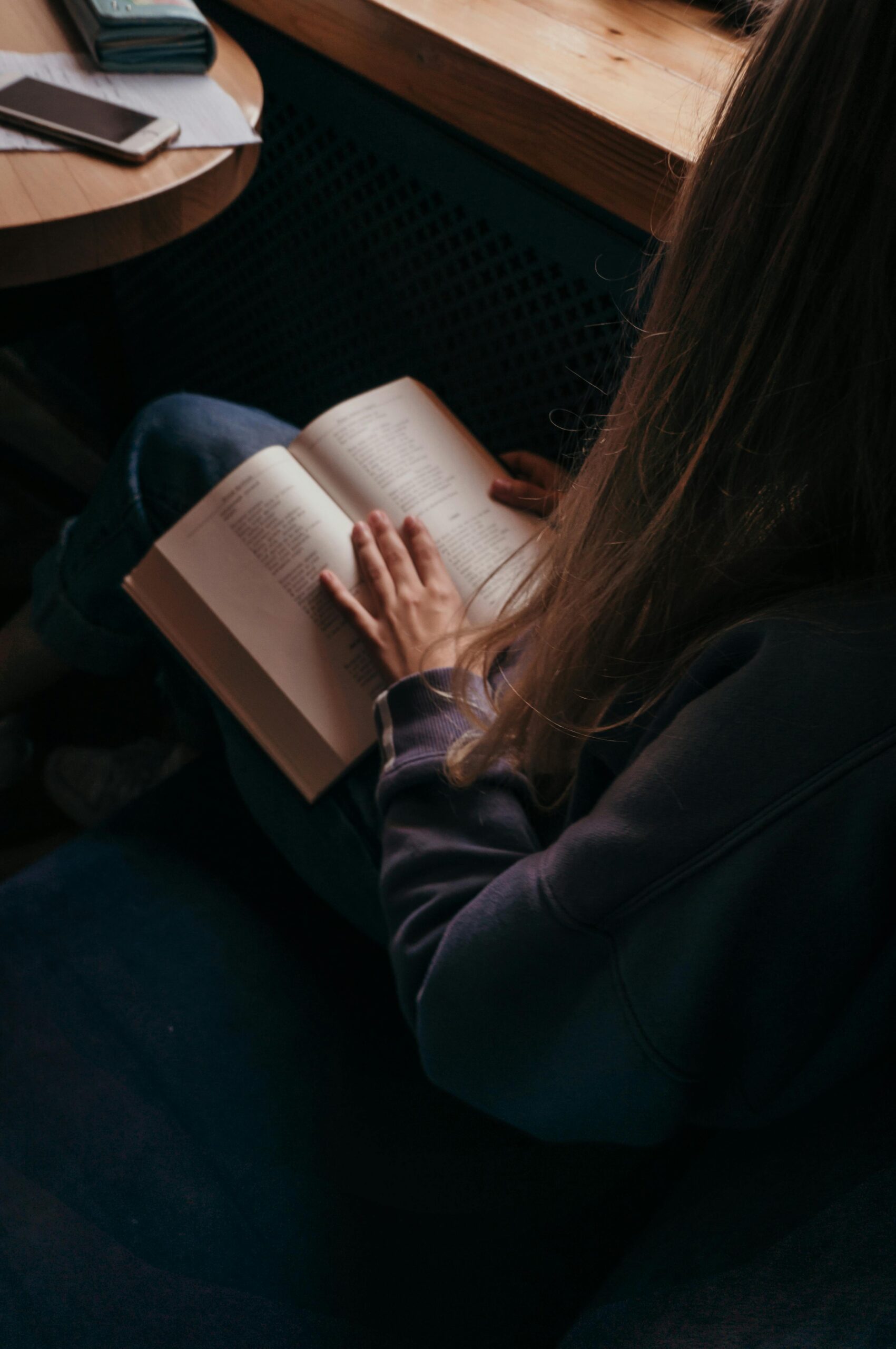 Mulher lendo um livro de autoconhecimento em um momento de reflexão profunda.