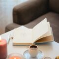 Caderno de anotações com chá e vela, representando rituais de reconexão espiritual e foco produtivo.