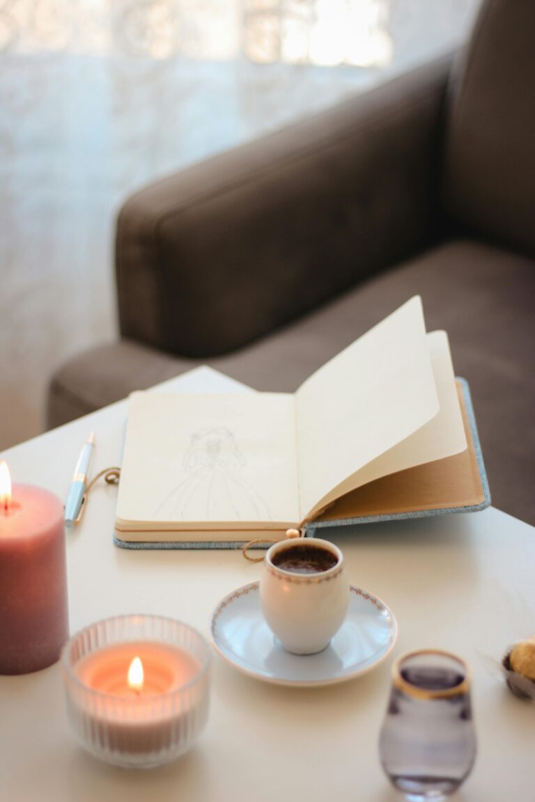 Caderno de anotações com chá e vela, representando rituais de reconexão espiritual e foco produtivo.